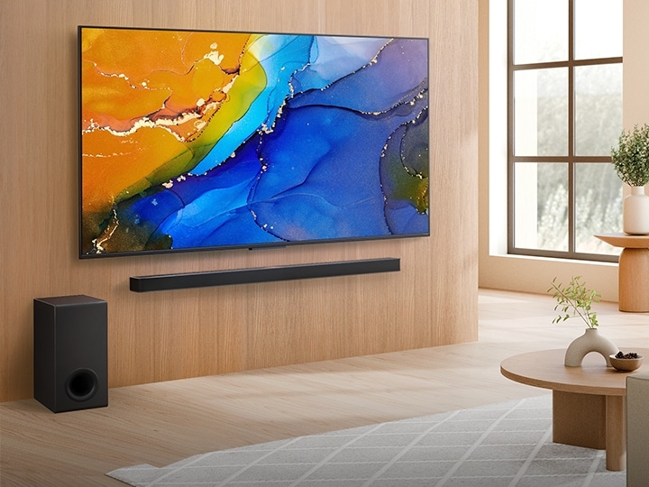تلفزيون LG QNED TV مثبت على الحائط فوق مكبر صوت LG Soundbar في مساحة معيشة عصرية. يصور تلفزيون LG QNED TV خلفية تجريدية ملونة.	