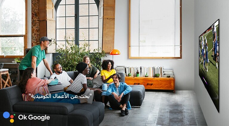 امرأة تشاهد كرة القدم على التلفزيون مع الأصدقاء وتطلب من مساعد جوجل البحث عن الأعمال الكوميدية