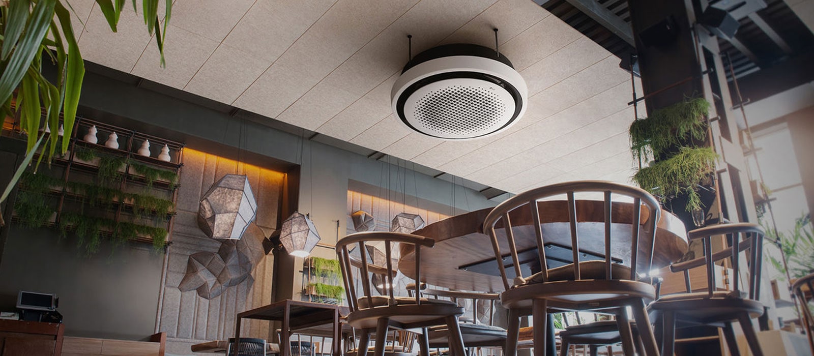 From an ant's perspective, a café unfolds, adorned with chairs, tables, and plants, while an LG round cassette is displayed at the ceiling.	
