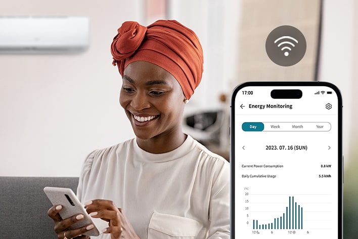 Woman using the LG ThinQ app with kW Manager to monitor energy usage and view consumption graphs on her phone.