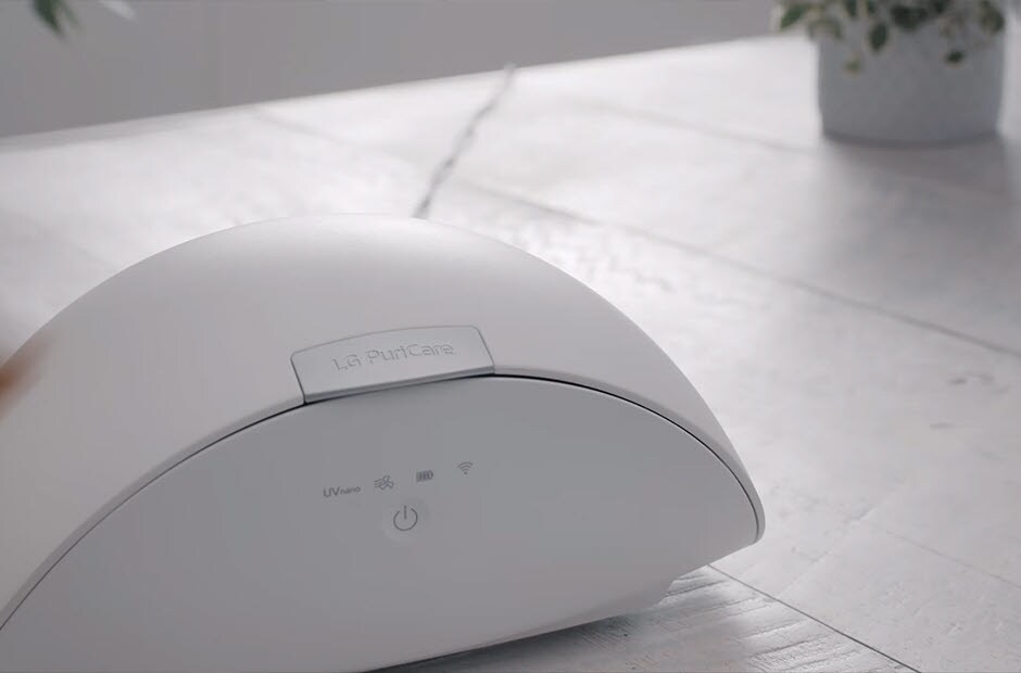 A video opens with the LG PuriCare Wearable Air Purifier Case sitting on a table and the LG PuriCare Wearable Air Purifier logo in the center. An icon with a faucet and hands beneath it appears with the words "Wash your hands before changing filters" in the center. The video cuts to a hand reaching in to open the case and then remove the mask. The words "Replacing the PuriCare Filter" appear in the upper left corner. The hands adeptly remove the filter lids and filters and replace them on both sides. The words "Pull open filter lid and replace the used filter with a new one." appear at the bottom throughout the process. When the hands remove the second side the words "Do the same for the other side" appear. Next the hands flip over the mask so the interior is showing and removes the face guard. The words "Separate the Face Guard from the device." appear at the bottom. The video cuts to the hands washing the face guard in the sink and the words "And wash it with mild soap and warm water" appear at the bottom. Next the hands re-attach the face guard to the mask. The words "Re-attach the clean and dry Face Guard to the device" appear at the bottom. The hands then insert a new inner filter and the words "and insert a new inner filter" appear at the bottom. The PuriCare case is shown on the table and the words "Using the PuriCare Wearable Air Purifier Case" appear in the top with "Keep your wearable device hygienically clean in between uses." appears at the bottom. A hand reaches in and opens the case and then inserts the mask and closes the lid. The words "The ThinQ app lets you check the status of the UVnano Care cycle" appears at the bottom. A phone screen appears on the left with the ThinQ app screen open to the Wearable Air Purifier Case page. In the top of the screen it reads "Monitor with ThinQ App" and on the bottom is reads "and the device filter drying cycle." The phone screen changes the page to show the usage data and the words at the bottom read "The app also lets you check usage history" and then completes the sentence with "and the remaining life of your filter to maintain effective filtration". The scene changes to show the case open and a hand places a phone and glasses inside. The words at the top read "Other uses for PuriCare Wearable Air Purifier Case" and at the bottom it reads "You can also use the case to Remove bacteria from and safely store items like smartphones and eye-glasses." The hand closes the case and the final scene shows the case on the table and the LG PuriCare Wearable Air Purifier logo ends the video.