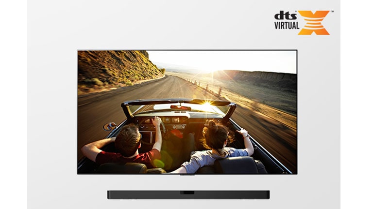 TV and Soundbar together in full view. TV shows a couple in an open roof car on the road driving into the sunset.
