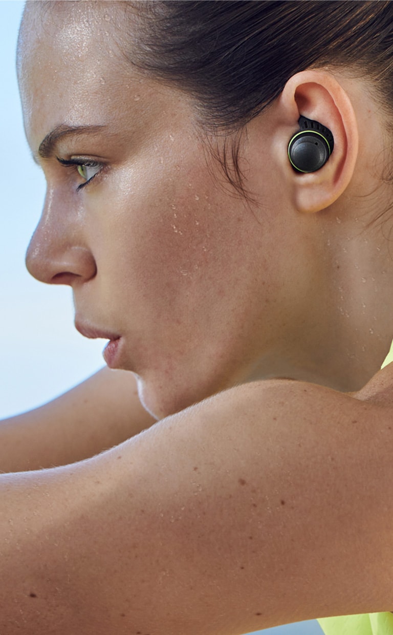 A woman is sweating and working out with TONE Free fit earbuds.