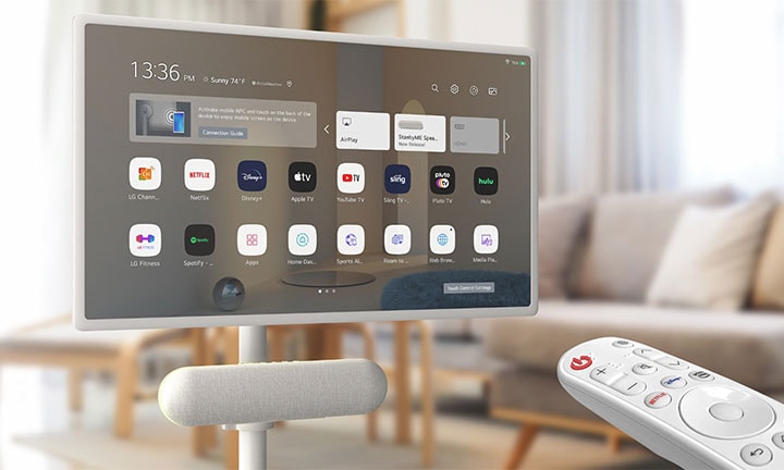 The LG XT7S speaker is attached on the LG StanbyME in the living room. The screen displays the home screen. On the bottom-right corner of the image, LG magic remote is shown.