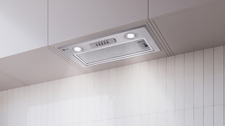 Built-in hood under a cabinet with its LED light turned on, illuminating the cooktop area.