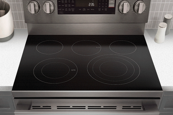 Stainless steel electric range with a black glass cooktop featuring five radiant heating elements and a digital display.