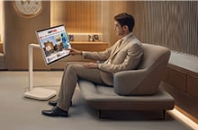 A man in the VIP lounge is reading the news on a LG Smart Monitor Swing.