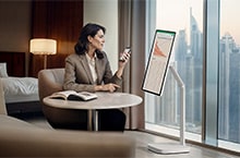 A woman is checking a chart on a LG Smart Monitor Swing in a hotel room.
