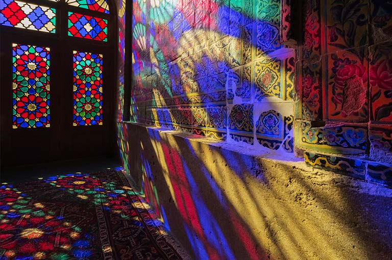 A scene showing light shining through stained glass windows to project colors onto a wall (play the video).