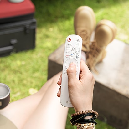 A hand is holding an LG remote.