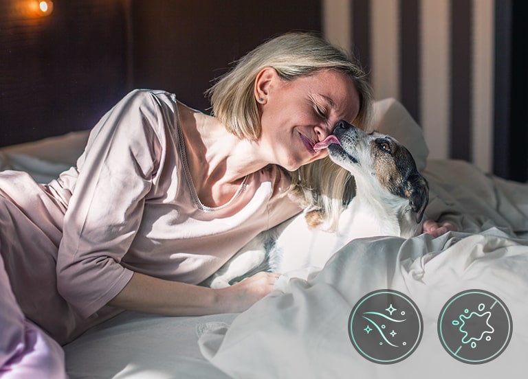 A woman and a dog are lying in bed