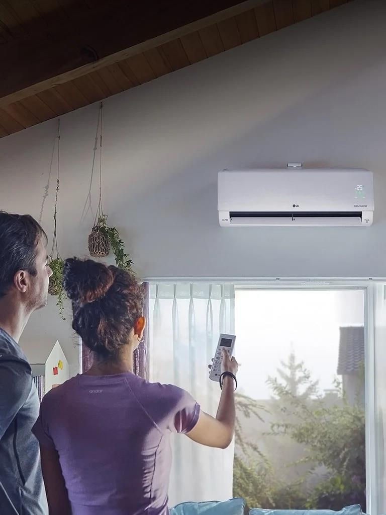 This is an image showing a man and a woman operating an air conditioner.