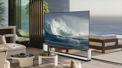 LG OLED Z2 is in a minimalist white room in front of a window that looks onto a forest of trees
