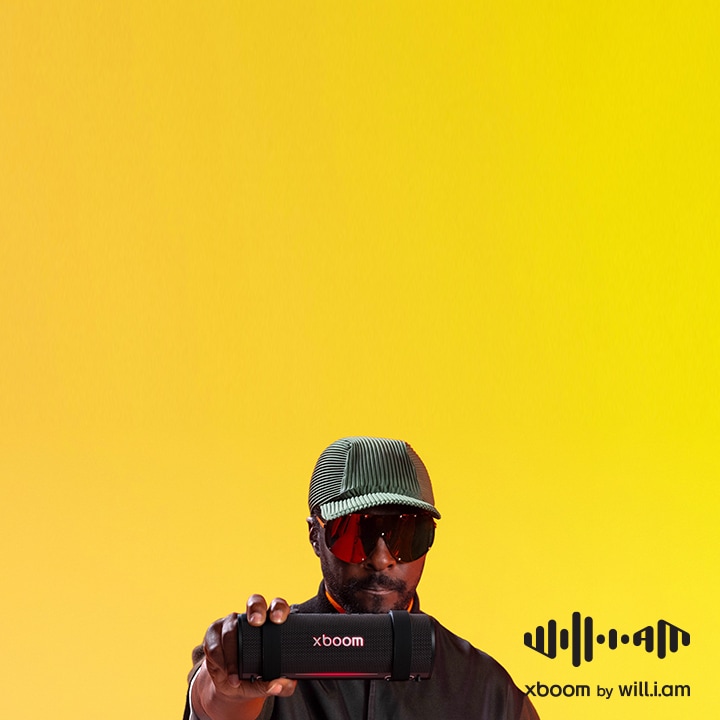 will.i.am in black outfit and sunglasses is holding xboom Grab on his shoulder.