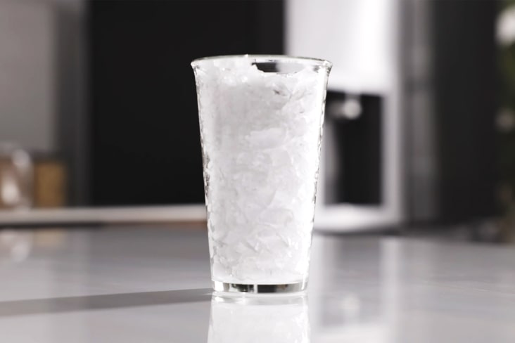 Klart glas fyllt med krossad is gjord i ett LG-kylskåp