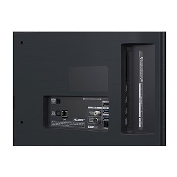 Stor vy över ett vardagsrum i ett lyxhem där en man tittar på en film på sin väggmonterade LG OLED TV. Tv:ns design smälter elegant in i väggen och inredningen.