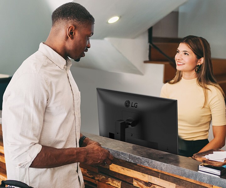 En kvinnlig receptionist pratar med en man i receptionen.	