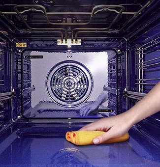 Bild på en person som torkar insidan av ugnen med en trasa.