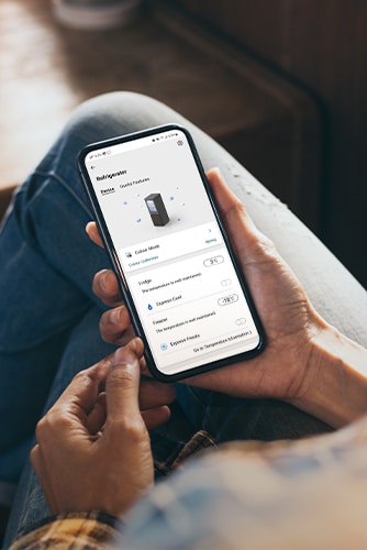 Bild som visar en app som låter dig justera inställningar i kylskåpet direkt i din smarta telefon som du håller i handen.