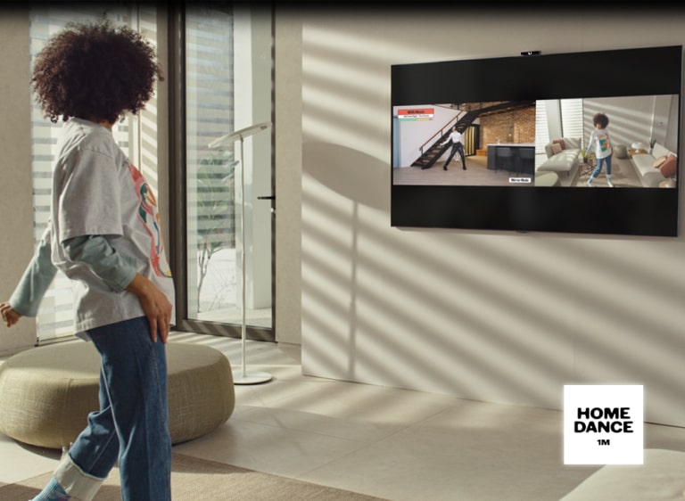 En person står framför TV:n och rör sig som om hon dansar. Skärmen är delad för att visa både personens egen bild och bilden av en person som demonstrerar dansen.
