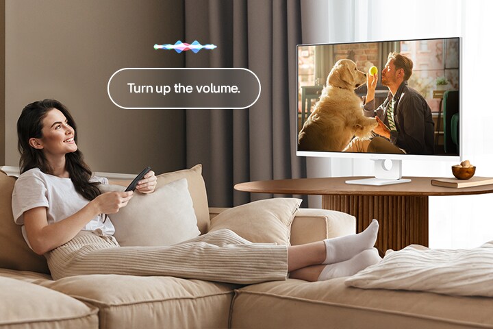 En kvinna höjer volymen på en LG Smart Monitor med en Magic Remote.	