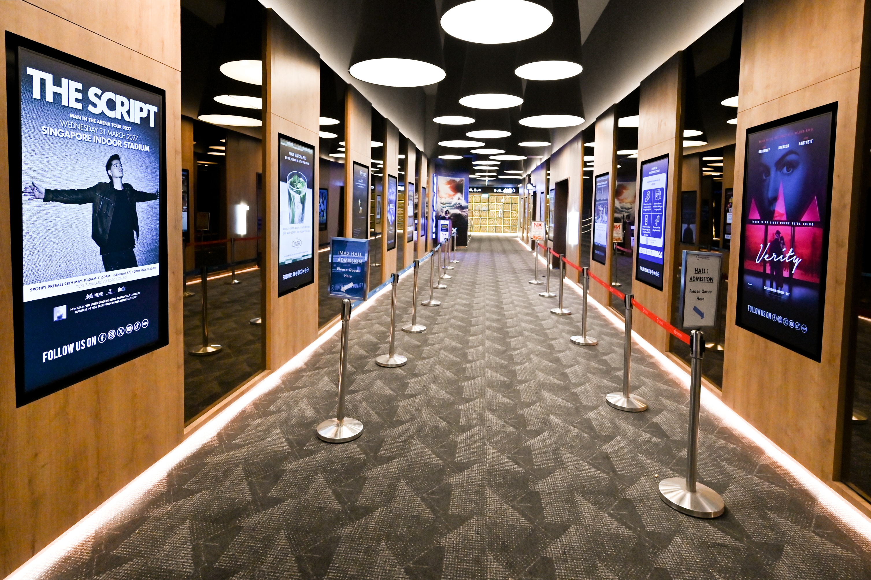 LG digital signage displays showcasing movie posters along a cinema corridor