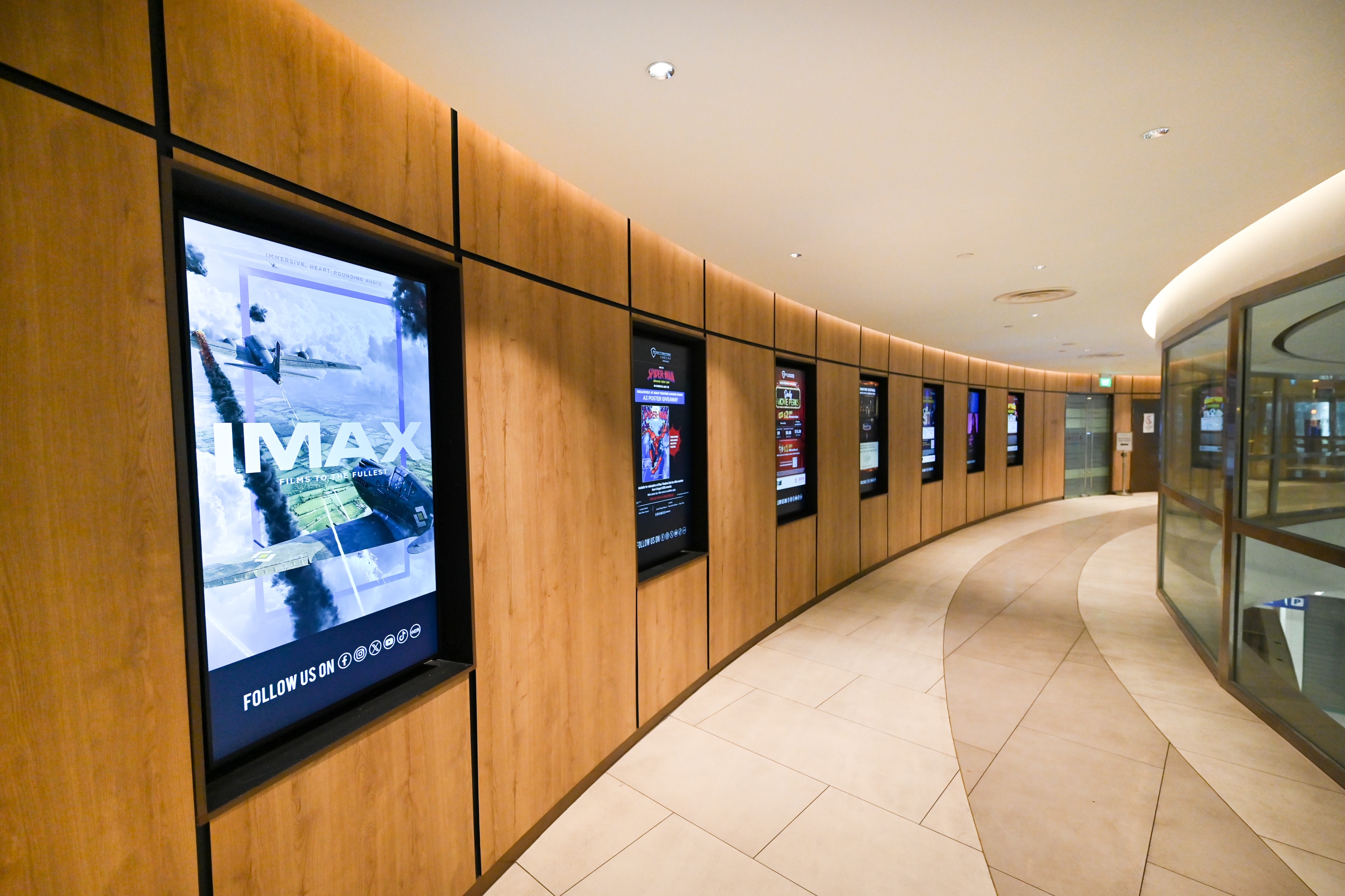 LG commercial digital signage displays installed along a curved cinema corridor at Shaw @ Lido