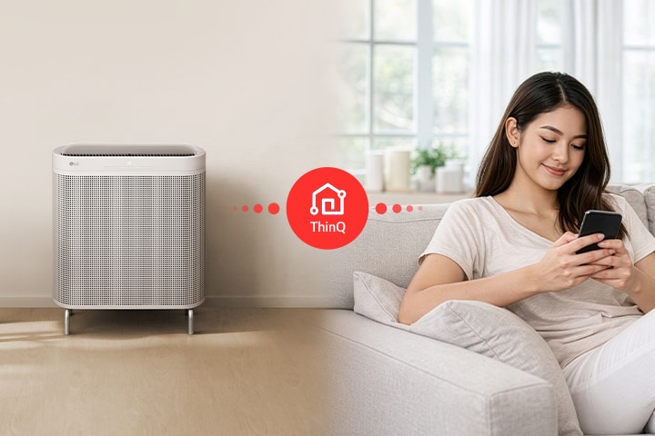 A woman using the LG ThinQ app on her smartphone to remotely control and monitor her LG air purifier from the sofa.