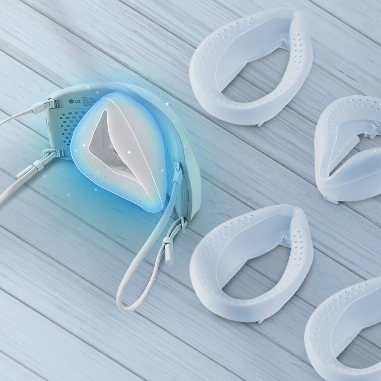 The top and interior of the mask is shown with the elastic fabric band connected in the back and highlighted in blue. Extra elastic fabric bands are on the table around the mask.