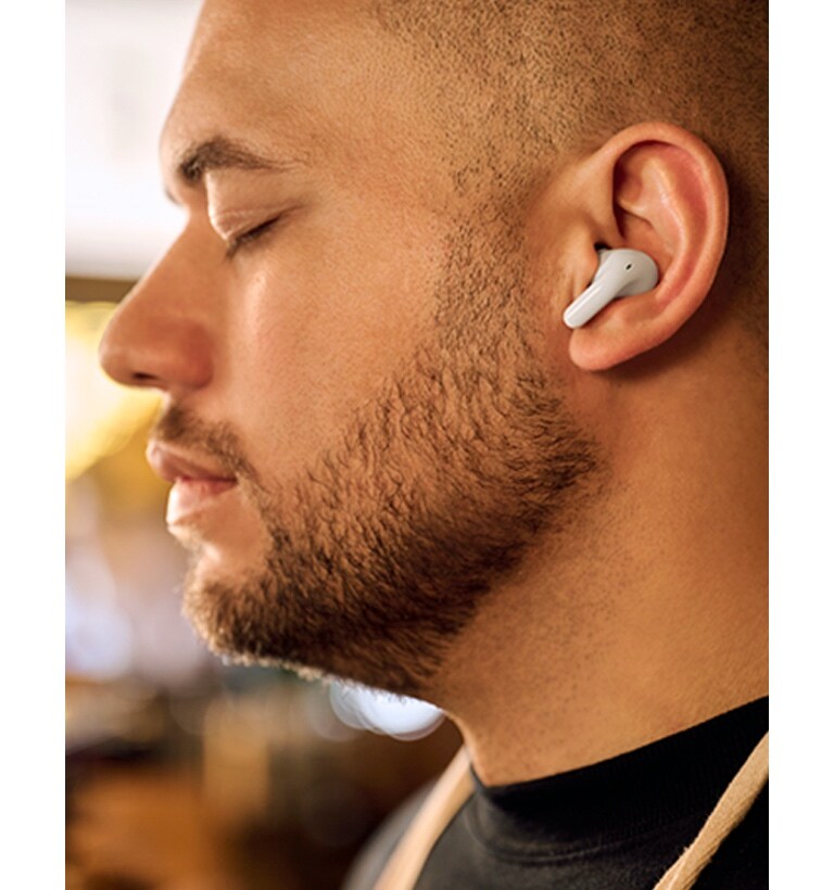 A man is wearing T60 earbuds and listening to music with his eyes closed.