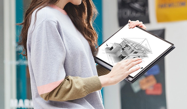 A woman is carrying her LG gram2in1, while she checking a design work on it on the way.