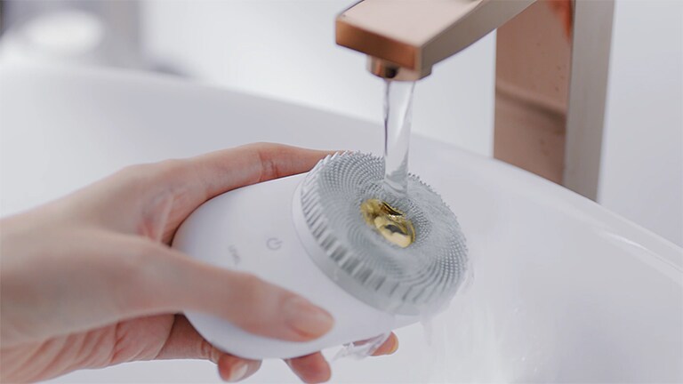 The person is washing the device with water and it implys ithat it is waterproof and it's easy to wash.