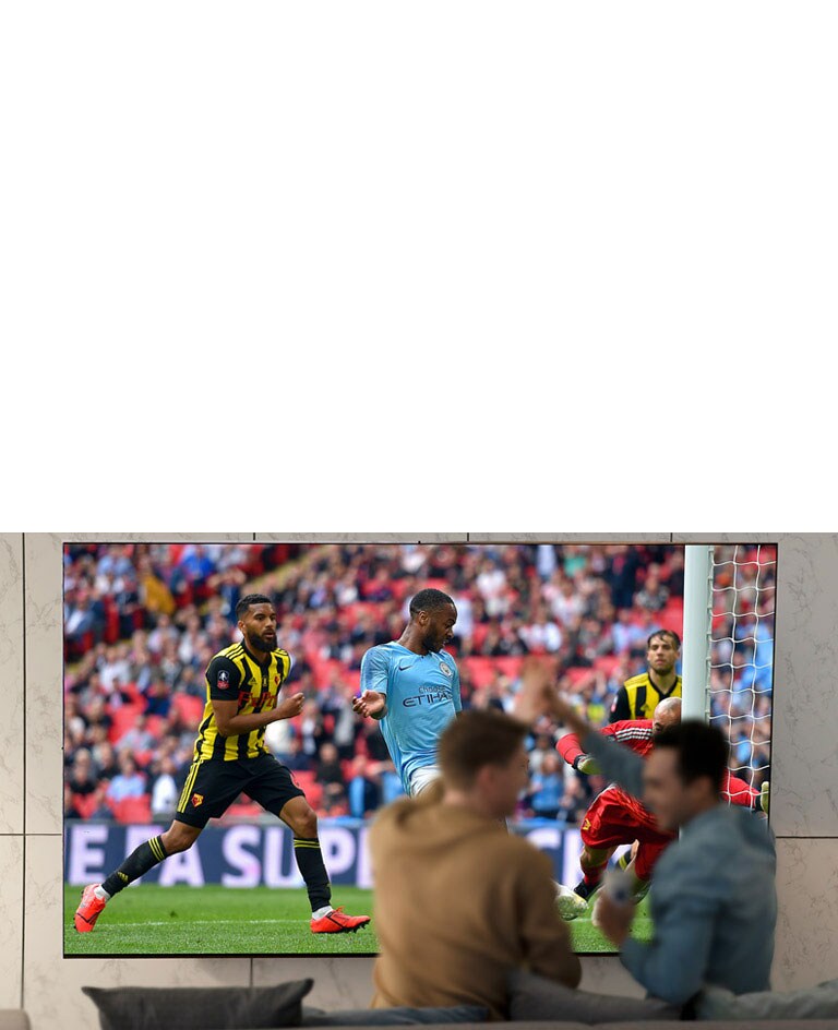 People watching sports game on TV in the living room with ultra large scree TV