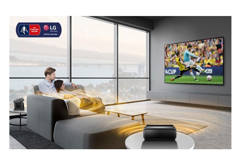 A man and women watching sports game on TV in the living room with Bluetooth rear speakers