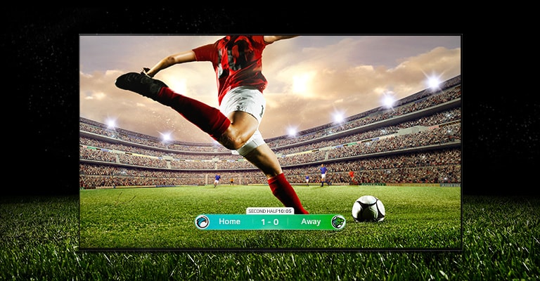   An image of the display showing a soccer game with a player in a red strip about to kick the ball across the stadium. The game score is visible at the bottom of the screen. The green grass from the pitch stretches beyond the screen to the black backdrop.