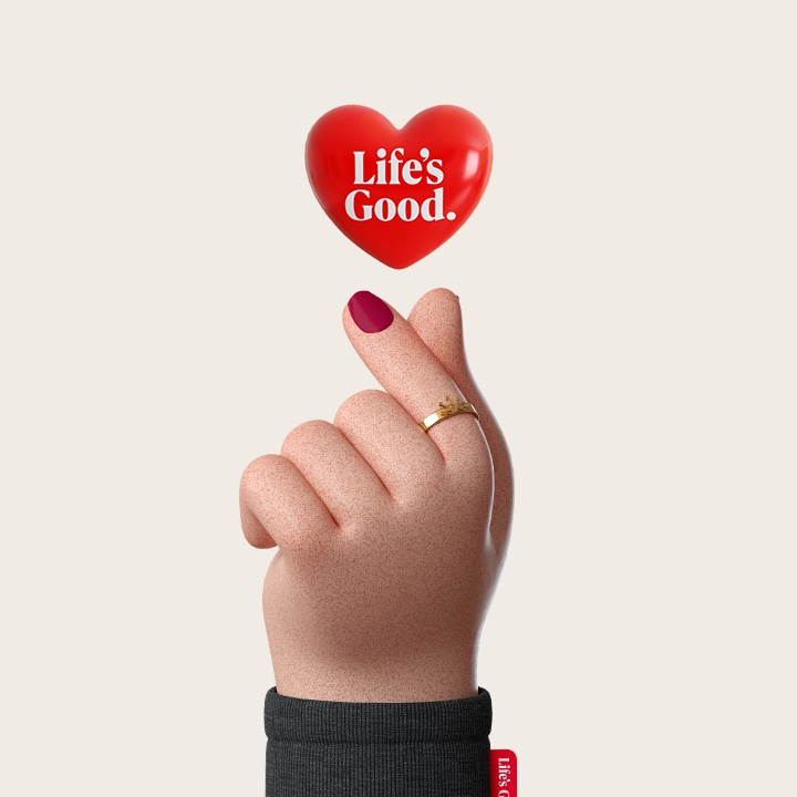 'A digital-style hand makes a finger-heart using the thumb and pointer finger, and above the gesture, a red heart shows LG's Life's Good logo.