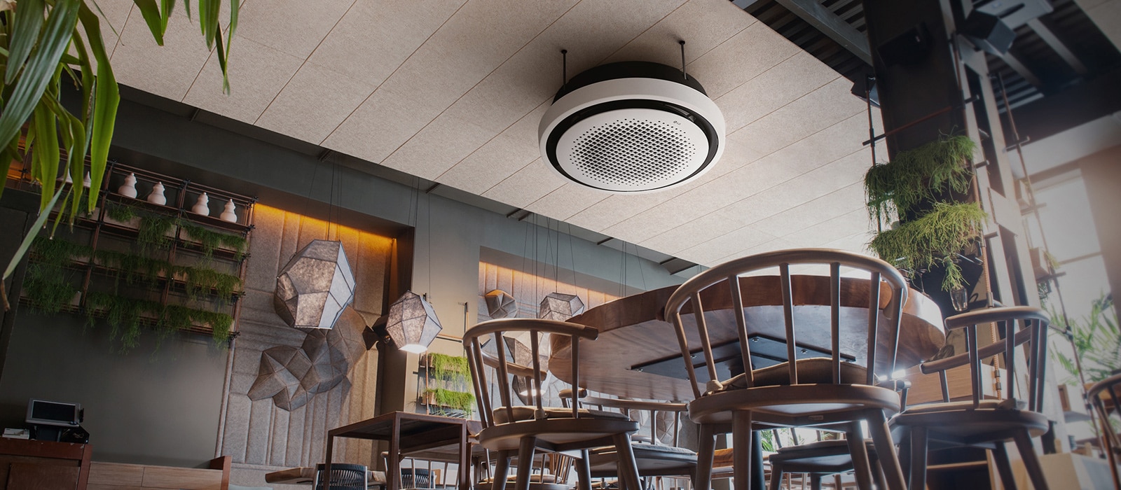 From an ant's perspective, a café unfolds, adorned with chairs, tables, and plants, while an LG round cassette is displayed at the ceiling.	