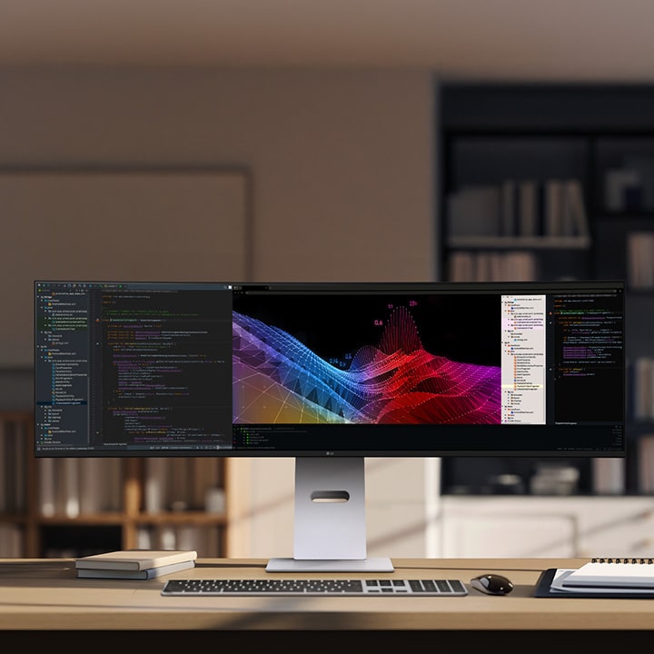 A modern home office setup featuring a large ultra-wide LG monitor displaying data dashboards and graphs, with a wireless keyboard and mouse on a wooden desk.