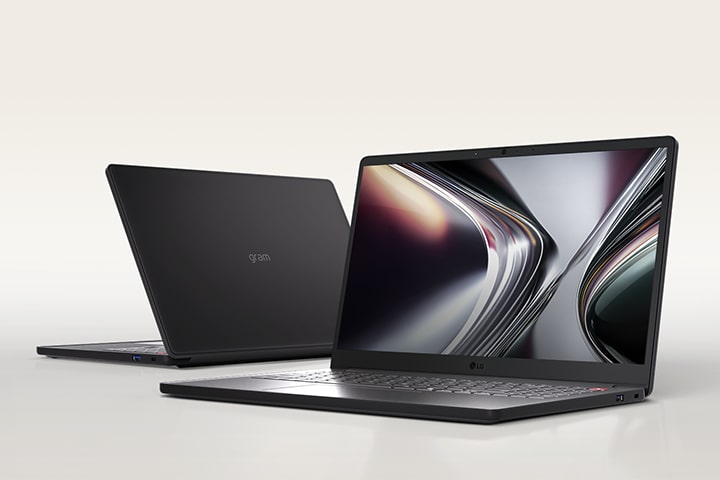 This image shows two lightweight laptops placed on a beige-toned background. The laptop on the left is open, showing the top surface, while the laptop on the right is open, showing the display.