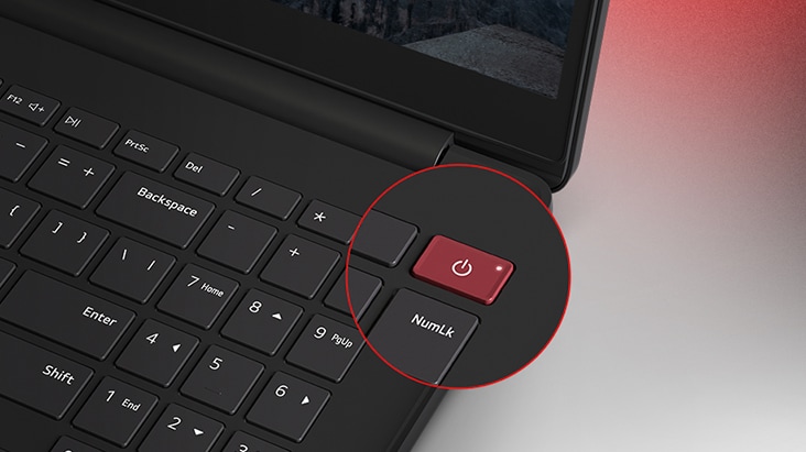 This image shows a close-up of a laptop keyboard. The focus is on a distinctive red power button located in the upper-right corner, highlighted with a circular zoom effect. 
