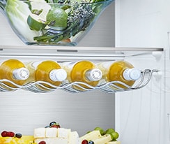 Inside view of LG fridge with neatly organized juice bottles, cheese, and vegetables on shelves.