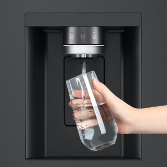 A person is getting water from the refrigerator dispenser in a cup