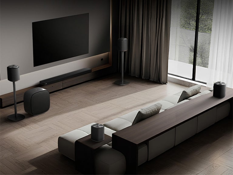 1) LG Sound Suite placed in a living room, demonstrating flexible speaker placement for an immersive home sound system 2) LG Sound Suite with Dolby Atmos FlexConnect technology detects each speaker’s location to optimize surround sound systems 3) Close-up of the LG Sound Suite W7 woofer with its driver showing deep bass performance down to 29.5 Hz