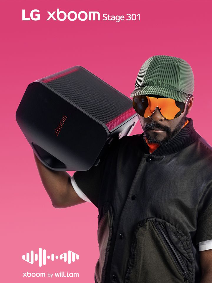 will.i.am in black outfit and sunglasses is holding xboom Stage 301 on his shoulder.	