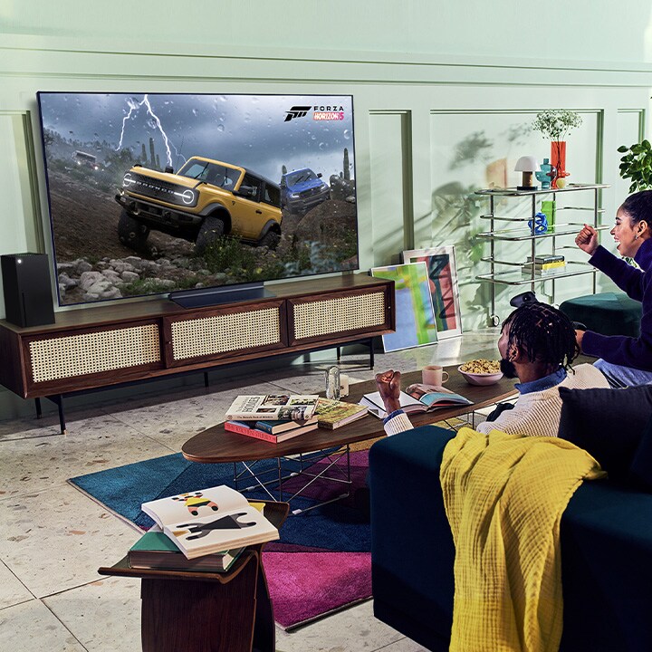 A person plays a racing game with an XBOX Series X controller on an LG OLED television
