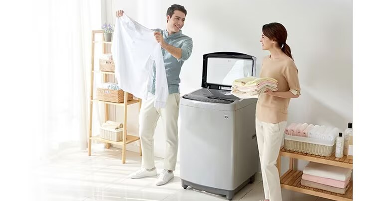 ผู้ชายถือเสื้อเชิ้ตสีขาว ผู้หญิงถือผ้าที่พับไว้ในมือและยืนข้างเครื่องซักผ้าฝาบน LG