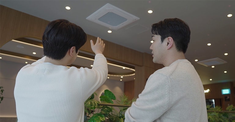 ผู้ชายสองคนกำลังคุยกันในขณะที่มองไปที่เครื่องปรับอากาศ
