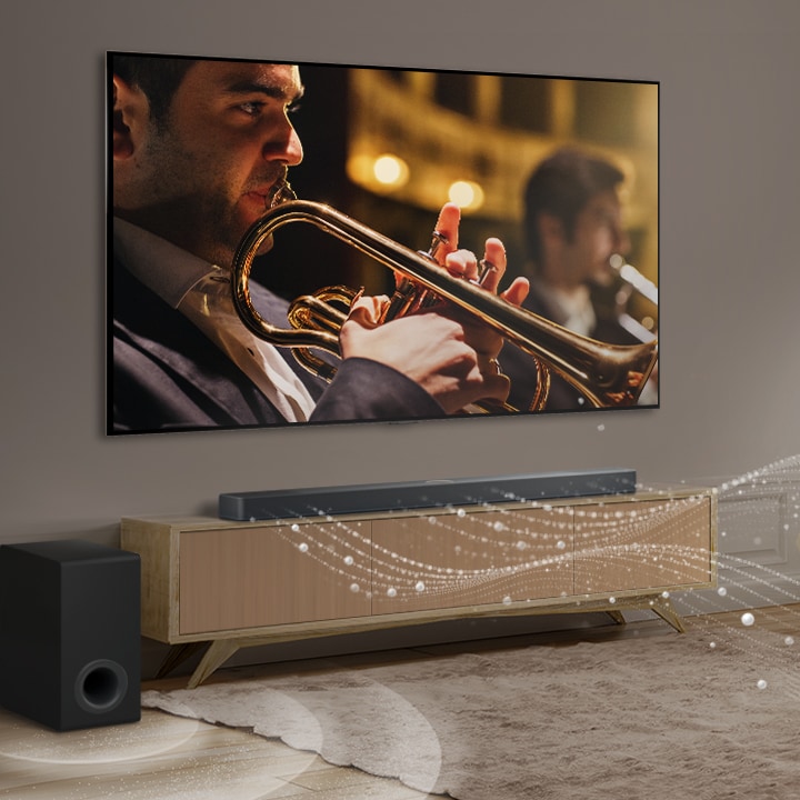 ซาวด์บาร์ ทีวี LG และซับวูฟเฟอร์ของ LG ตั้งอยู่ในอพาร์ตเมนต์ในเมืองที่ทันสมัย ​​ซาวด์บาร์ของ LG ปล่อยคลื่นเสียงสามสายที่ประกอบด้วยหยดน้ำสีขาวที่ลอยไปตามพื้นด้านล่าง ถัดจากซาวด์บาร์คือซับวูฟเฟอร์ที่สร้างเอฟเฟกต์เสียงจากด้านล่าง โดยรวมแล้ว พวกมันสร้างเอฟเฟกต์โดมทั่วทั้งห้อง