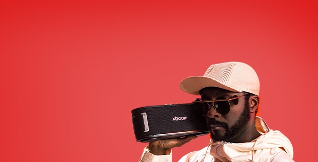 will.i.am ใส่ชุดขาวและแว่นกันแดด กำลังถือ xboom Bounce ใกล้กับใบหน้าของเขา