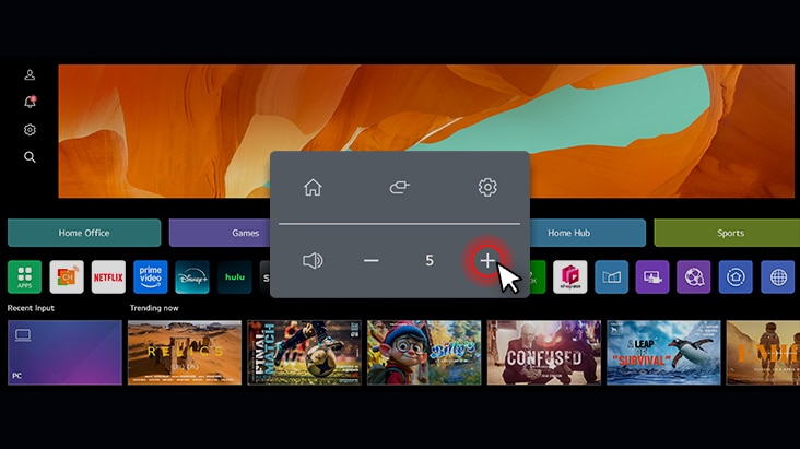 Smart monitor interface displaying volume adjustment with a cursor clicking the plus button, surrounded by streaming apps and category tabs like Home Office, Games, and Sports.